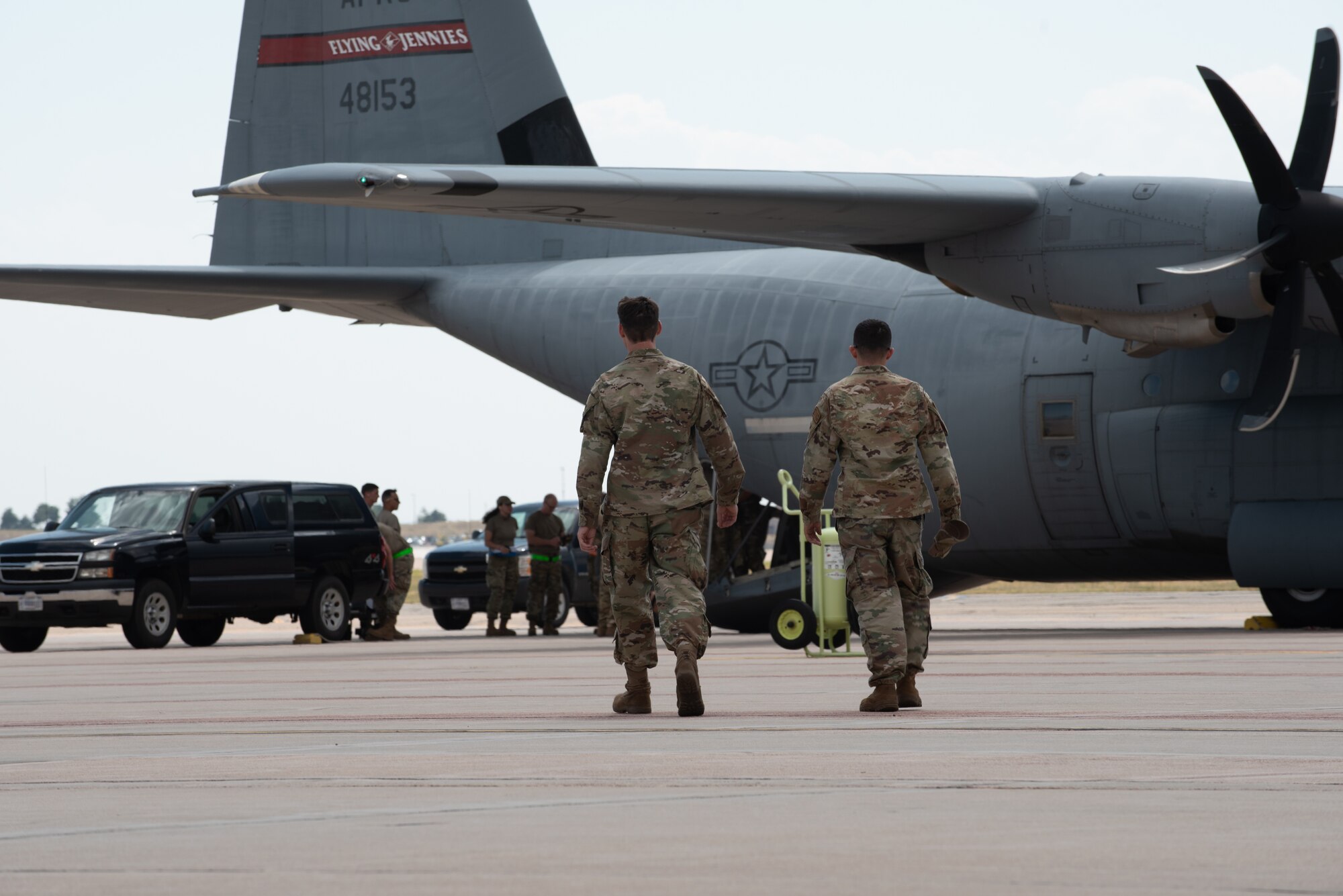 airman walk towards a recently landed c-130 to help the unloading process