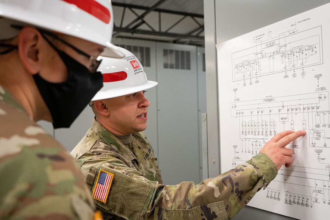 U.S. Army Sgt. Logan Cummings, back, examines an electrical one-line diagram alongside fellow 249th Engineer Battalion Charlie Company Prime Power production specialist Staff Sgt. Daniel Dipilato, during Exercise Empire Rising 2021 at the U.S. Naval Academy in Annapolis, Md., July 13, 2021. The U.S. Army Corps of Engineers, Baltimore District; 249th Engineer Battalion Charlie Company Prime Power; and emergency management partners helped enable community restoration efforts in the National Capital Region by successfully assessing temporary emergency power needs for critical facilities after a mock hurricane. (U.S. Army photo by Greg Nash)
