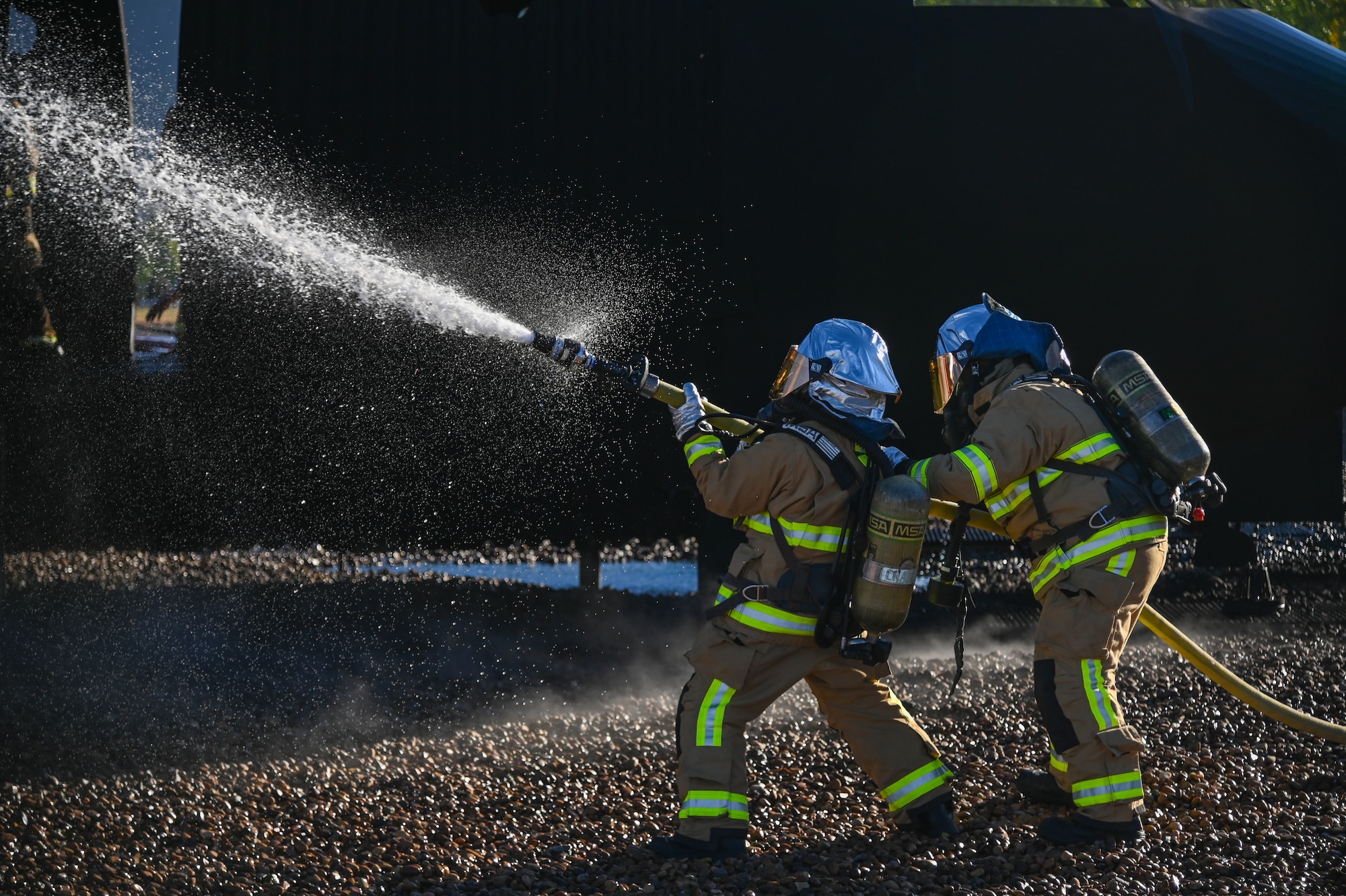 Firefighters from 775th Civil Engineering Squadron fight a fire at the aircraft fire simulator Sept. 22, 2021, at Hill Air Force Base, Utah. Squadrons from the 75th Air Base Wing participated in a phase II readiness exercise where they were assessed on performing tasks in an austere environment. (U.S. Air Force photo by Cynthia Griggs)