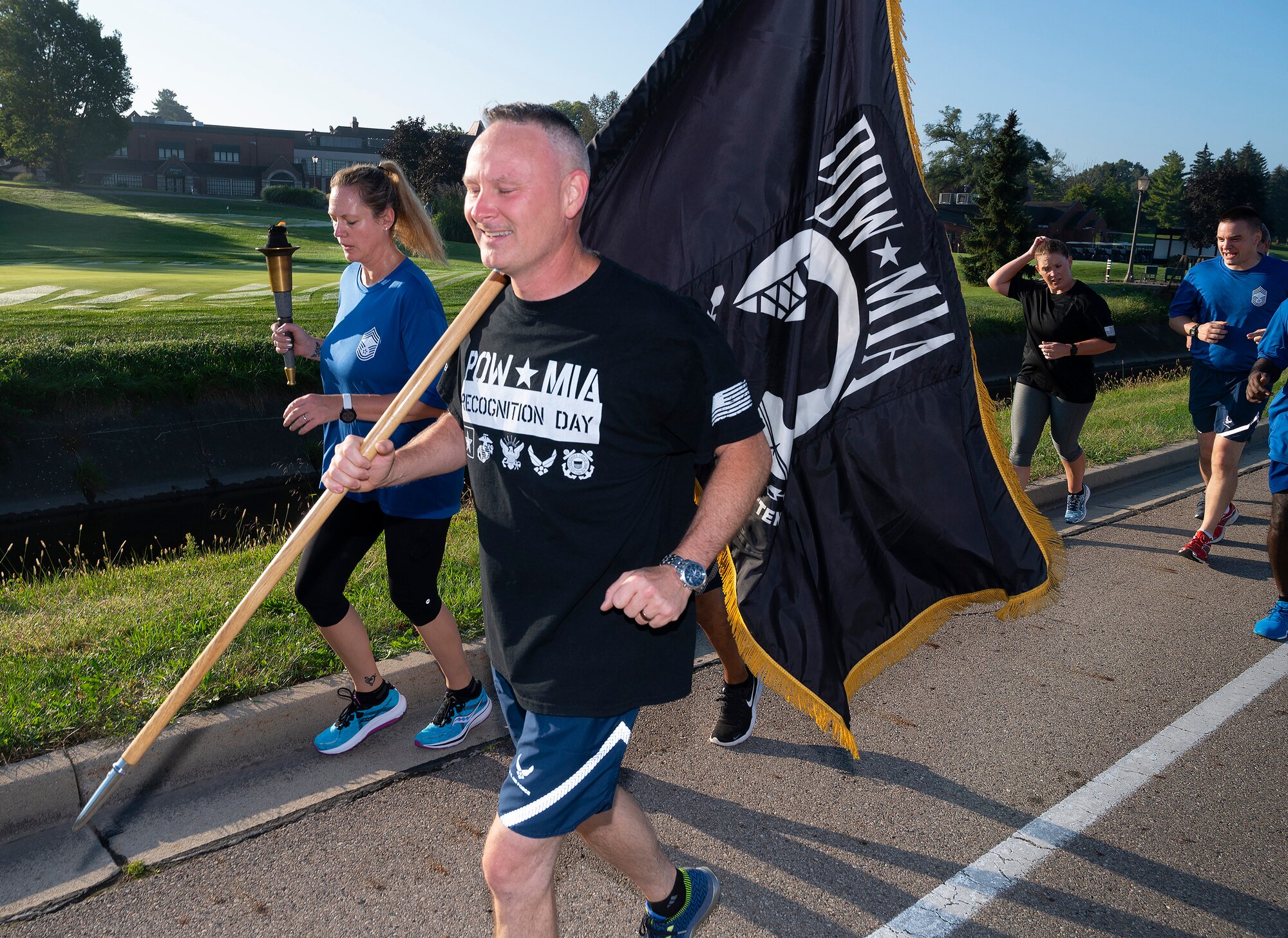 Chief Master Sgt. Shawn Plowman, 88th Diagnostics and Therapeutics Squadron, carries the POW/MIA Flag while Chief Master Sgt. Lindsey Wolf, Air Force Materiel Command command paralegal, holds up the torch as they lead a Wright-Patterson Chiefs Group delegation on the annual POW/MIA run Sept. 17, 2021. Runners delivered the torch and flag to the POW/MIA Recognition Day wreath-laying ceremony at Wright-Patterson Air Force Base, Ohio. National POW/MIA Recognition Day is marked each year on the third Friday in September to remember those held captive or missing in action. (U.S. Air Force photo by R.J. Oriez)