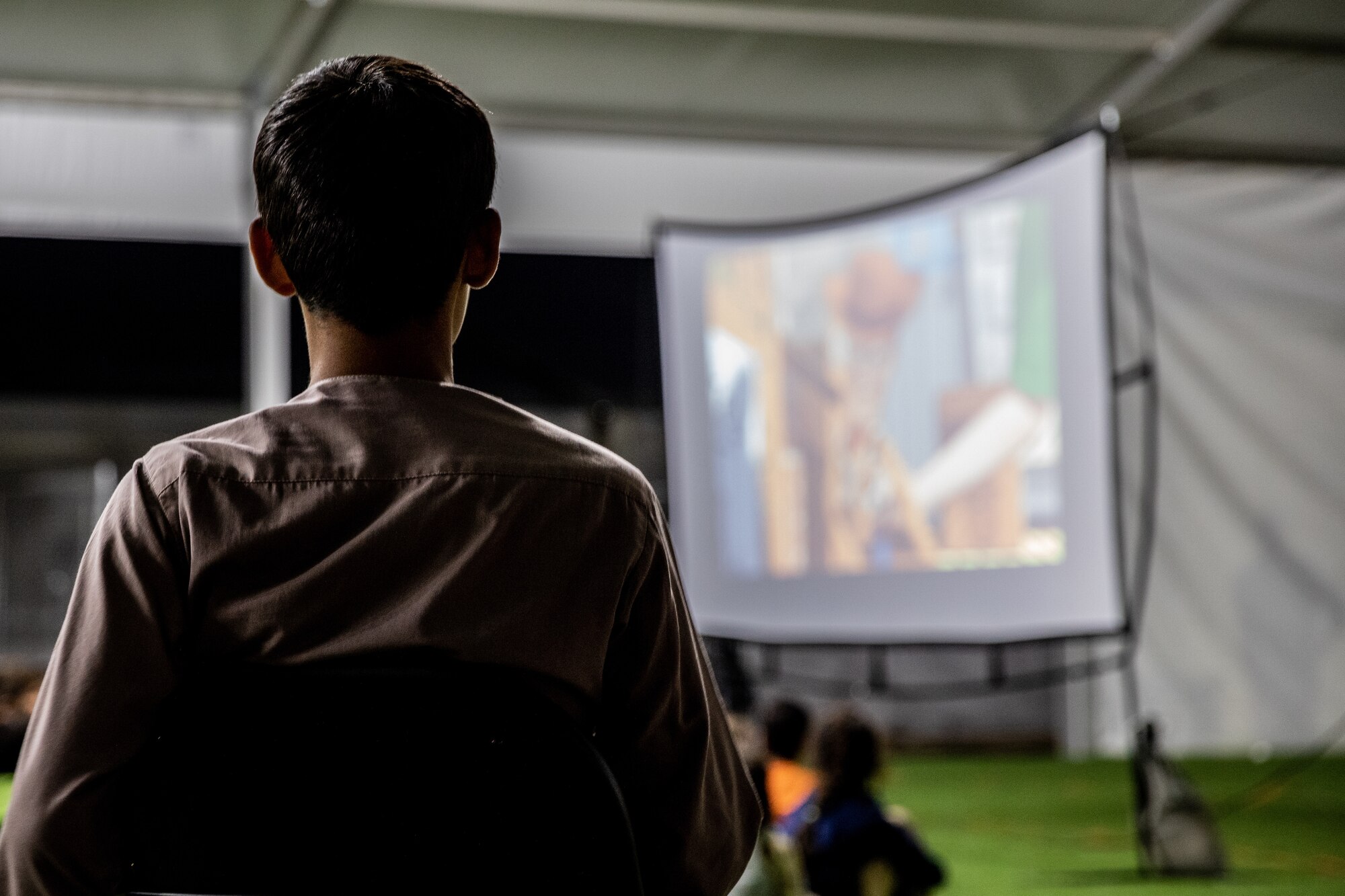 Afghan evacuees watch a movie set up by the Department of Homeland Security as a recreational activity in support of Operation Allies Welcome on Holloman Air Force Base, New Mexico, Sept. 20, 2021. The Department of Defense, through the U.S. Northern Command, and in support of the Department of State and Department of Homeland Security, is providing transportation, temporary housing, medical screening, and general support for at least 50,000 Afghan evacuees at suitable facilities, in permanent or temporary structures, as quickly as possible. This initiative provides Afghan evacuees essential support at secure locations outside Afghanistan. (U.S. Army photo by Spc. Nicholas Goodman)