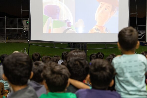 Afghan evacuees watch a movie set up by the Department of Homeland Security as a recreational activity in support of Operation Allies Welcome on Holloman Air Force Base, New Mexico, Sept. 20, 2021. The Department of Defense, through the U.S. Northern Command, and in support of the Department of State and Department of Homeland Security, is providing transportation, temporary housing, medical screening, and general support for at least 50,000 Afghan evacuees at suitable facilities, in permanent or temporary structures, as quickly as possible. This initiative provides Afghan evacuees essential support at secure locations outside Afghanistan. (U.S. Army photo by Spc. Nicholas Goodman)