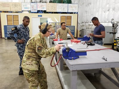 Air Force lieutenant colonel shows how to operate an impact driver to Jamaican service members.