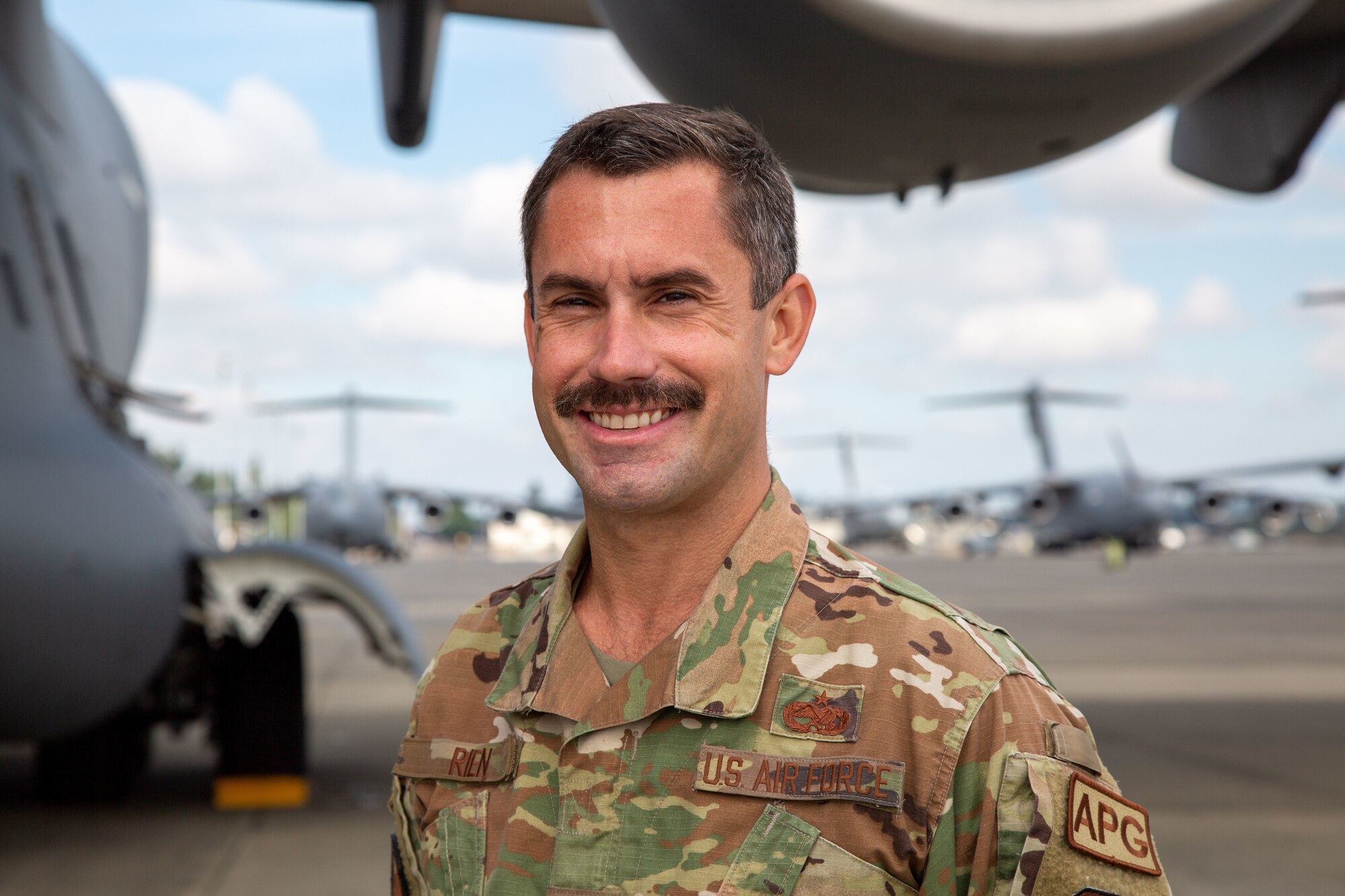 Airman poses underneath wing of aircraft