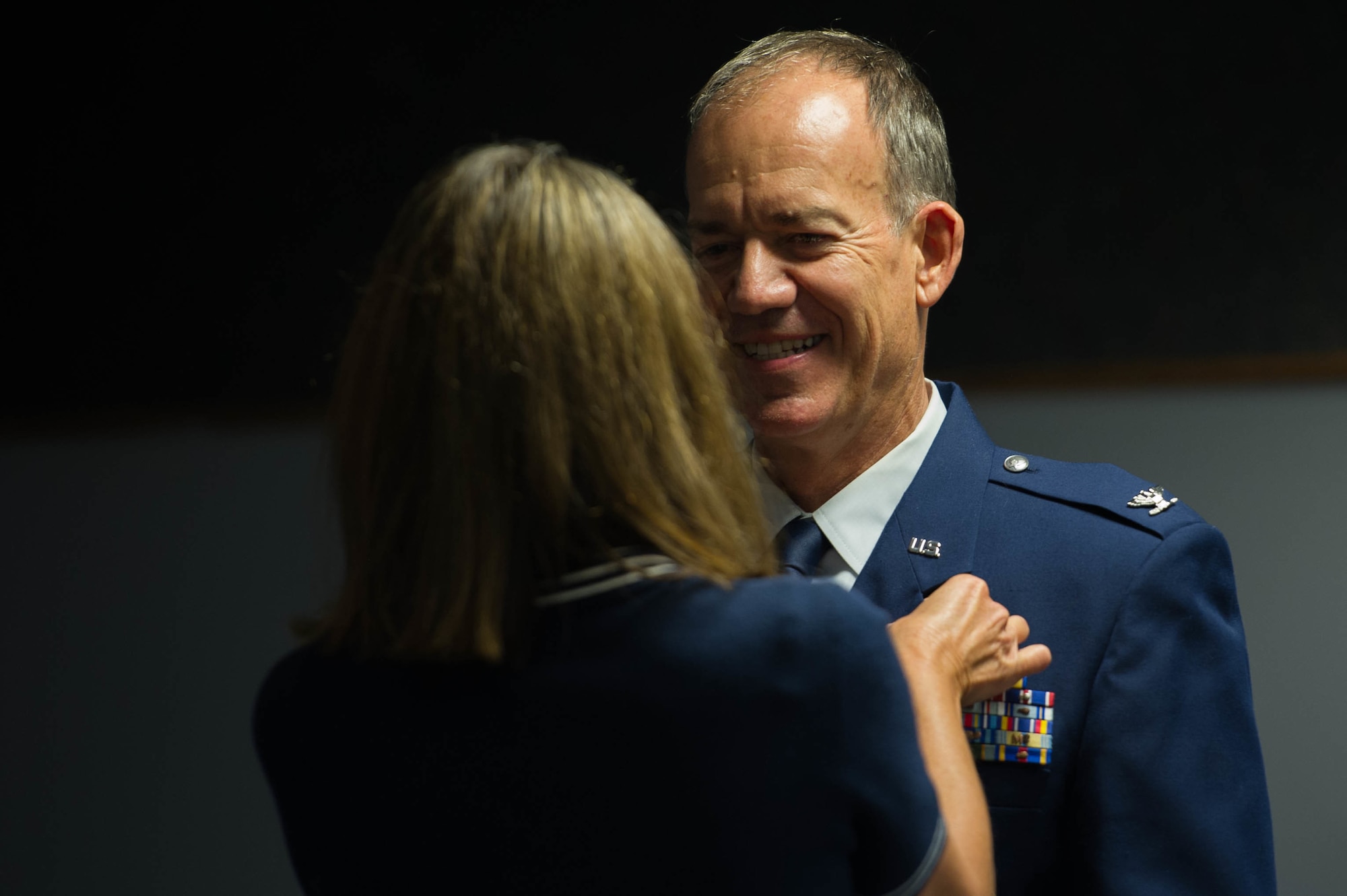 Woman fastens a retirement pin on airman.