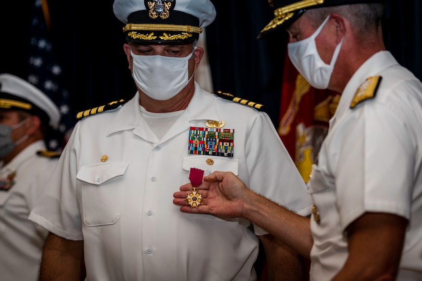 Rear Adm. Pete Garvin, right, commander, Naval Education and Training Command (NETC), presents Capt. Keith Dowling, commanding officer, Center for Explosive Ordnance Disposal and Diving (CEODD), with the Legion of Merit award during a change of command ceremony, Sept. 22.