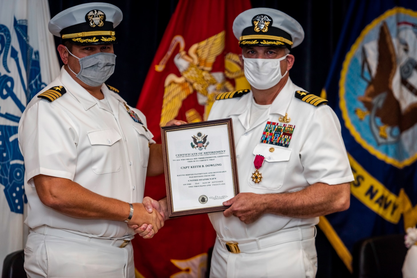 Capt. Dean Muriano, left, commanding officer, Center for Explosive Ordnance Disposal and Diving, presents Capt. Keith Dowling with a certificate of retirement during a change of command for the Center for Explosive Ordnance Disposal and Diving (CEODD) and retirement ceremony for Dowling.  Dowling concluded his nearly 38-year career as CEODD’s commanding officer.