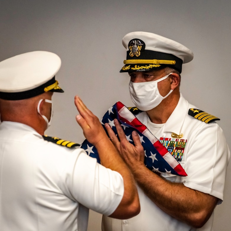 After 38 years of naval service, Capt. Keith Dowling, right, receives a U.S. flag during his retirement ceremony, Sept. 22.  The ceremony was held during a change of command for the Center for Explosive Ordnance Disposal and Diving (CEODD), where Dowling concluded his career as CEODD’s commanding officer.