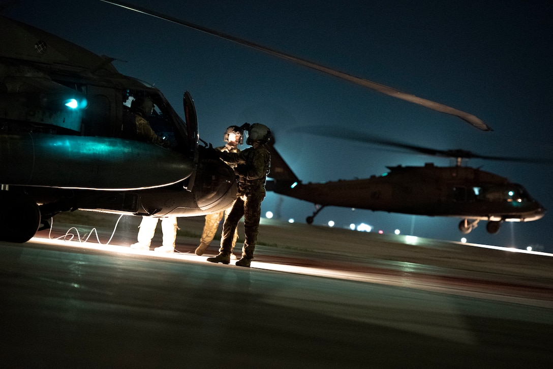 U.S. Army Soldiers from Task Force Black Cat inspect a UH-60 Black Hawk during a joint K-9 helicopter training mission