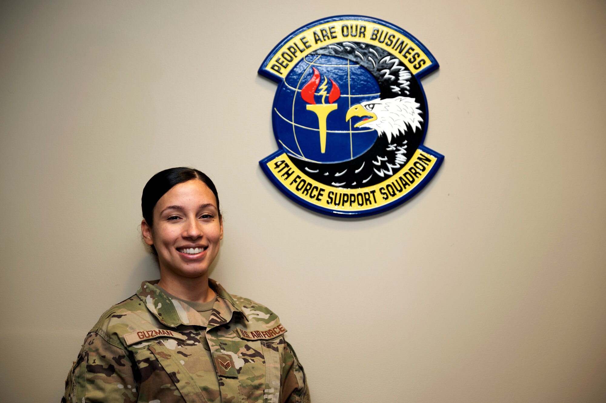 Senior Airman Teresa Guzman, 4th Force Support Squadron self-assessment program manager, poses for a photo with the 4th FSS logo at Seymour Johnson Air Force Base, North Carolina, Sept. 22, 2021. Guzman has been in for three years and plans to continue her service past her current enlistment. (U.S. Air Force photo by Senior Airman David Lynn)