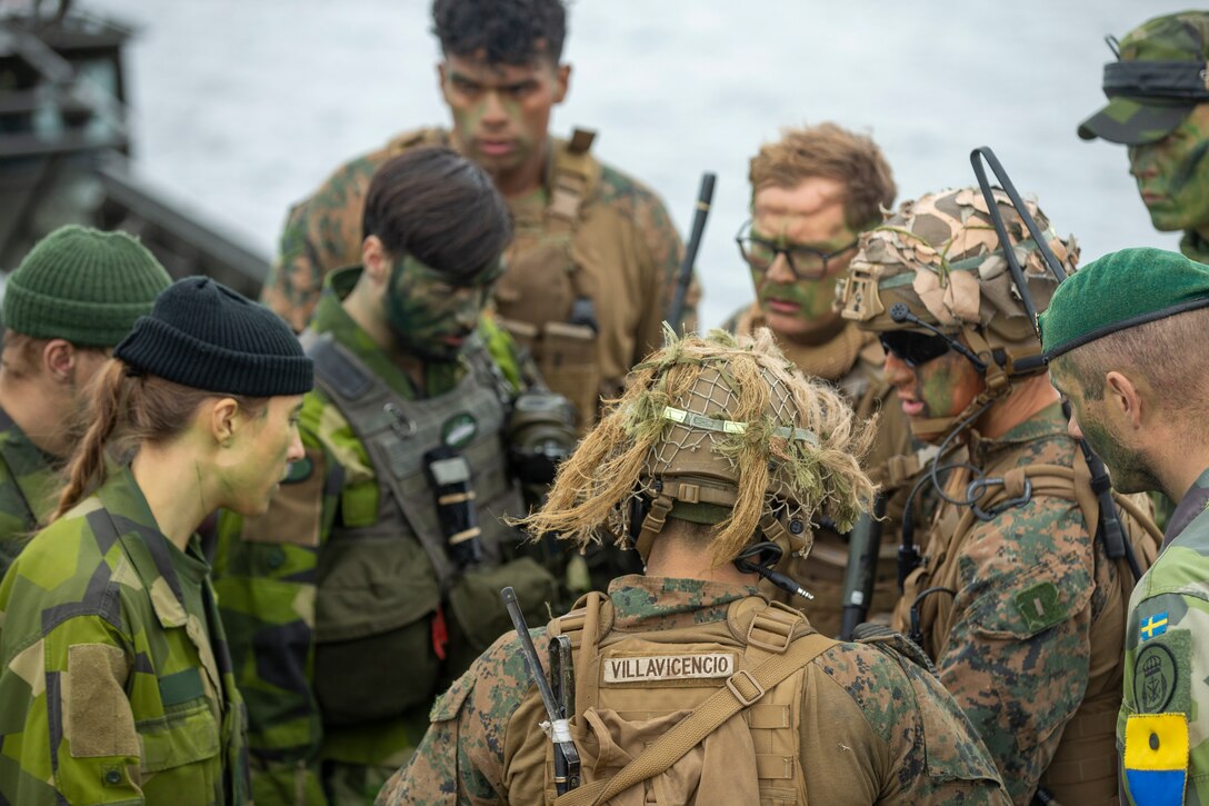 Swedish Marines with the 204th Rifle Company, 2nd Marine Battalion, 1st Swedish Marine Regiment, and U.S. Marines with 1st Battalion, 6th Marine Regiment, 2d Marine Division, discuss operations orders during Exercise Archipelago Endeavor, Berga Naval Base, Sweden, Sept. 22, 2021. Exercise Archipelago Endeavor is a multi-domain, field training exercise that focuses on regional engagements by conducting partnered, limited-scale maritime raids, and military-to-military collaboration and strengthens operational capabilities and strategic cooperation between the U.S. Marine Corps and Swedish Armed Forces. (U.S. Marine Corps photo by 1st Lt. Paul Ortiz)