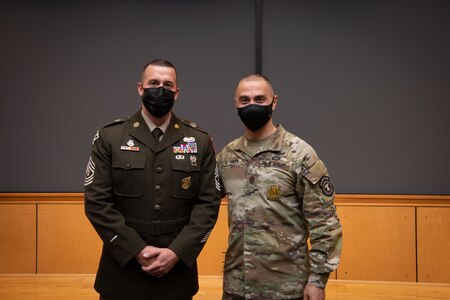 two men in army uniforms pose for a photo.