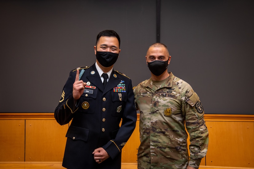 two men in army uniforms pose for a photo.