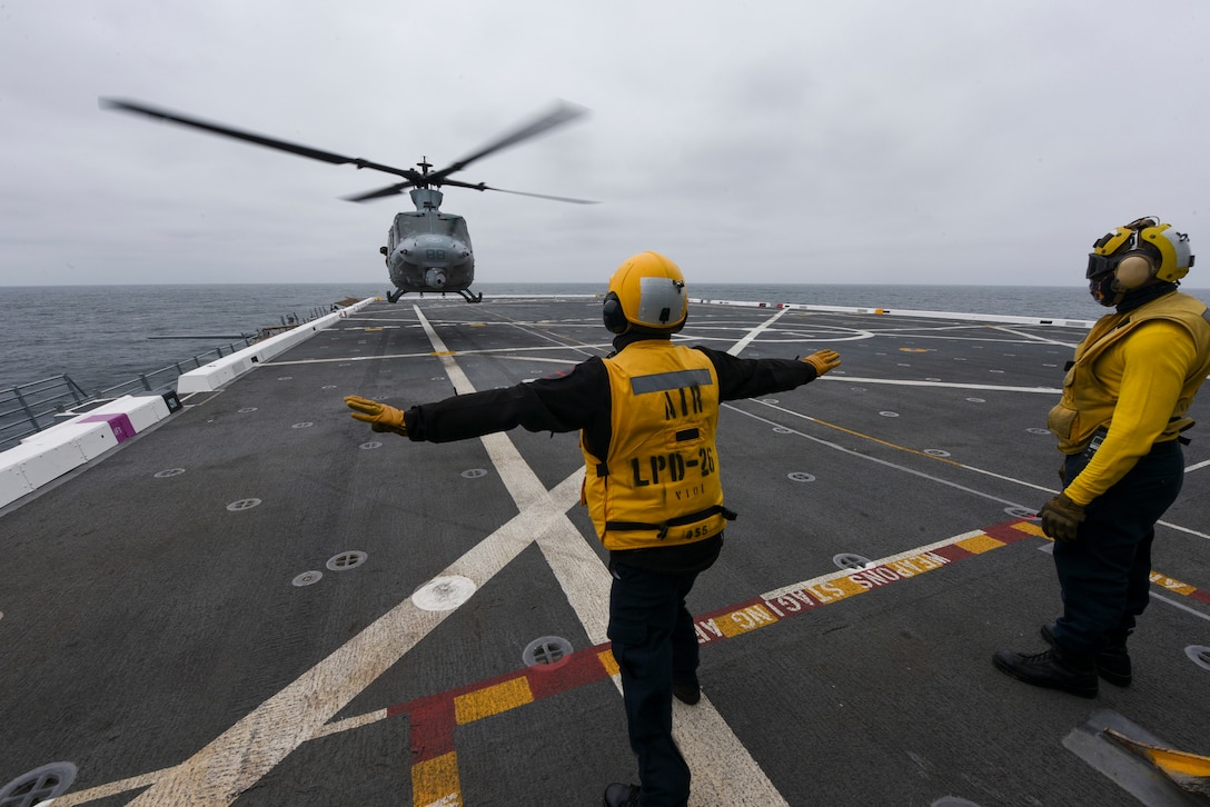 A military helicopter lands on a ship.