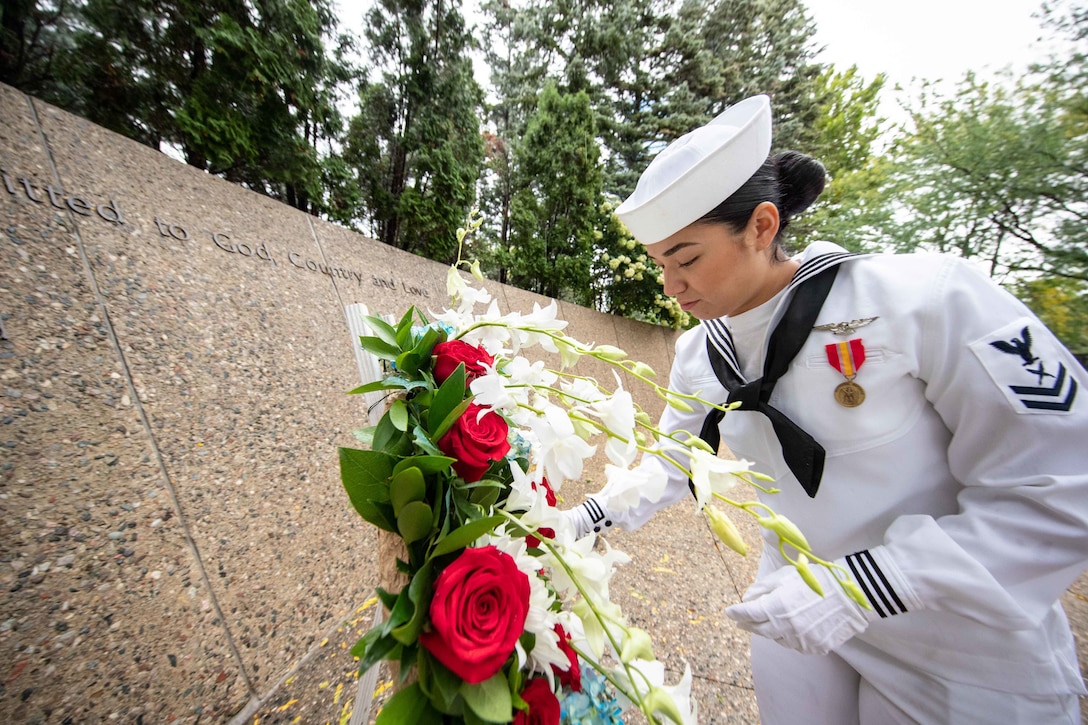 A sailor places flowers at a memorial marker.