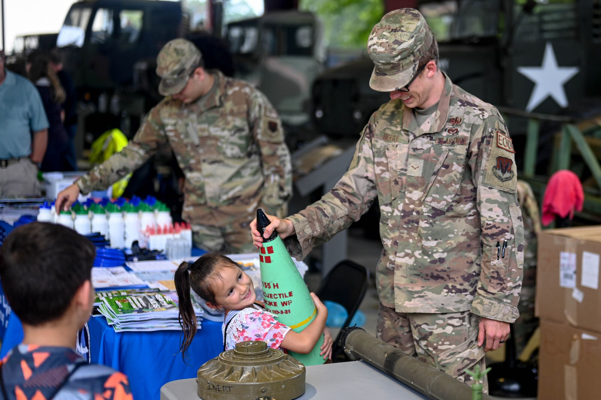 U.S. Air Force Airman 1st Class Matthew Beegle, explosive ordnance disposal technician, 633rd Civil Engineer Squadron, demonstrates the size of an inert 155 millimeters  round by letting a child hold it during the Touch-A-Truck event on Joint Base Langley-Eustis, Virginia, September 9, 2021. Explosive Ordnance Disposal is one of the first responder agencies that took part in the Touch-A-Truck event. (U.S. Air Force photo by Senior Airman Johnny Foister)