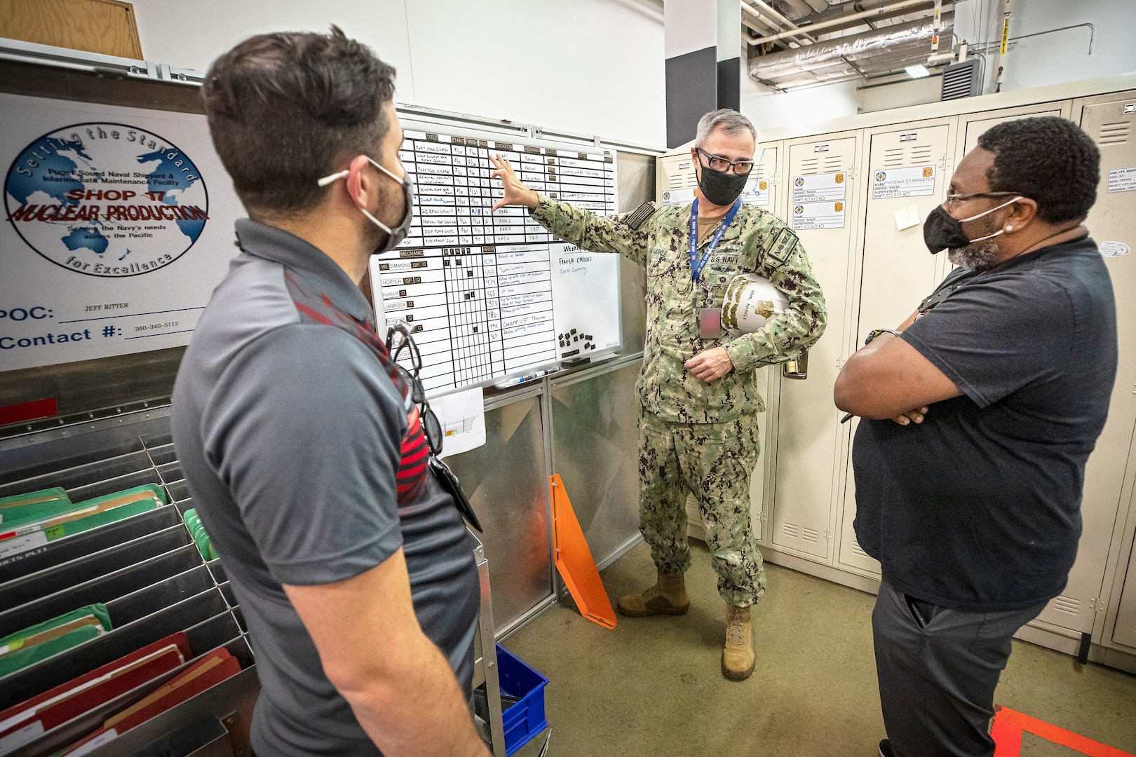 Rear Adm. Howard B. Markle, deputy commander, Logistics, Maintenance and Industrial Operations, Naval Sea Systems Command, talks with Chris Harty, Shop 11/17 Shipfitter and Sheet Metal, general foreman, and Timothy Tibbs, Shop 11, Shipfitter, supervisor, about the use of crew boards Aug. 26, 2021, during a tour of the Building 1124 CVN Maintenance Complex at Puget Sound Naval Shipyard & Intermediate Maintenance Facility in Bremerton, Washington. (PSNS & IMF photo by Scott Hansen)