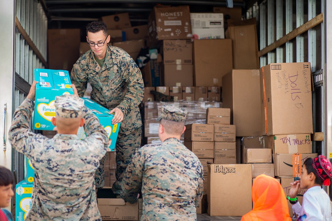Marines unload boxes of supplies from a truck.