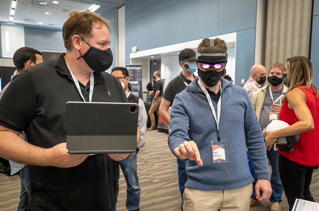 Lifecycle Engineering representative Cory Kozlowski, left, helps Brian Hoglund, a Keyport computer scientist, use a mixed-reality headset Wednesday, Aug. 25, 2021, during Puget Sound Naval Shipyard & Intermediate Maintenance Facility's 2021 Technology Showcase at the Kitsap Conference Center in Bremerton, Washington. (PSNS & IMF photo by Scott Hansen)