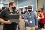 Lifecycle Engineering representative Cory Kozlowski, left, helps Brian Hoglund, a Keyport computer scientist, use a mixed-reality headset Wednesday, Aug. 25, 2021, during Puget Sound Naval Shipyard & Intermediate Maintenance Facility's 2021 Technology Showcase at the Kitsap Conference Center in Bremerton, Washington. (PSNS & IMF photo by Scott Hansen)