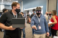 Lifecycle Engineering representative Cory Kozlowski, left, helps Brian Hoglund, a Keyport computer scientist, use a mixed-reality headset Wednesday, Aug. 25, 2021, during Puget Sound Naval Shipyard & Intermediate Maintenance Facility's 2021 Technology Showcase at the Kitsap Conference Center in Bremerton, Washington. (PSNS & IMF photo by Scott Hansen)
