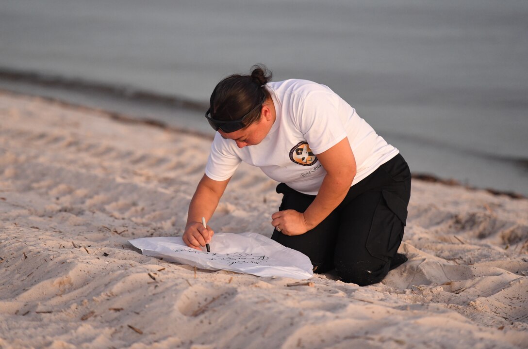 Diana Aird, 81st Security Forces Squadron officer, writes a message on a lantern during the Air Force Families Forever Fallen Hero Sky Lantern Lighting on the Biloxi Beach, Mississippi, Sept. 24, 2021. The event, hosted by Keesler Air Force Base, included eco-friendly sky lanterns released in honor of fallen heroes. (U.S. Air Force photo by Kemberly Groue)