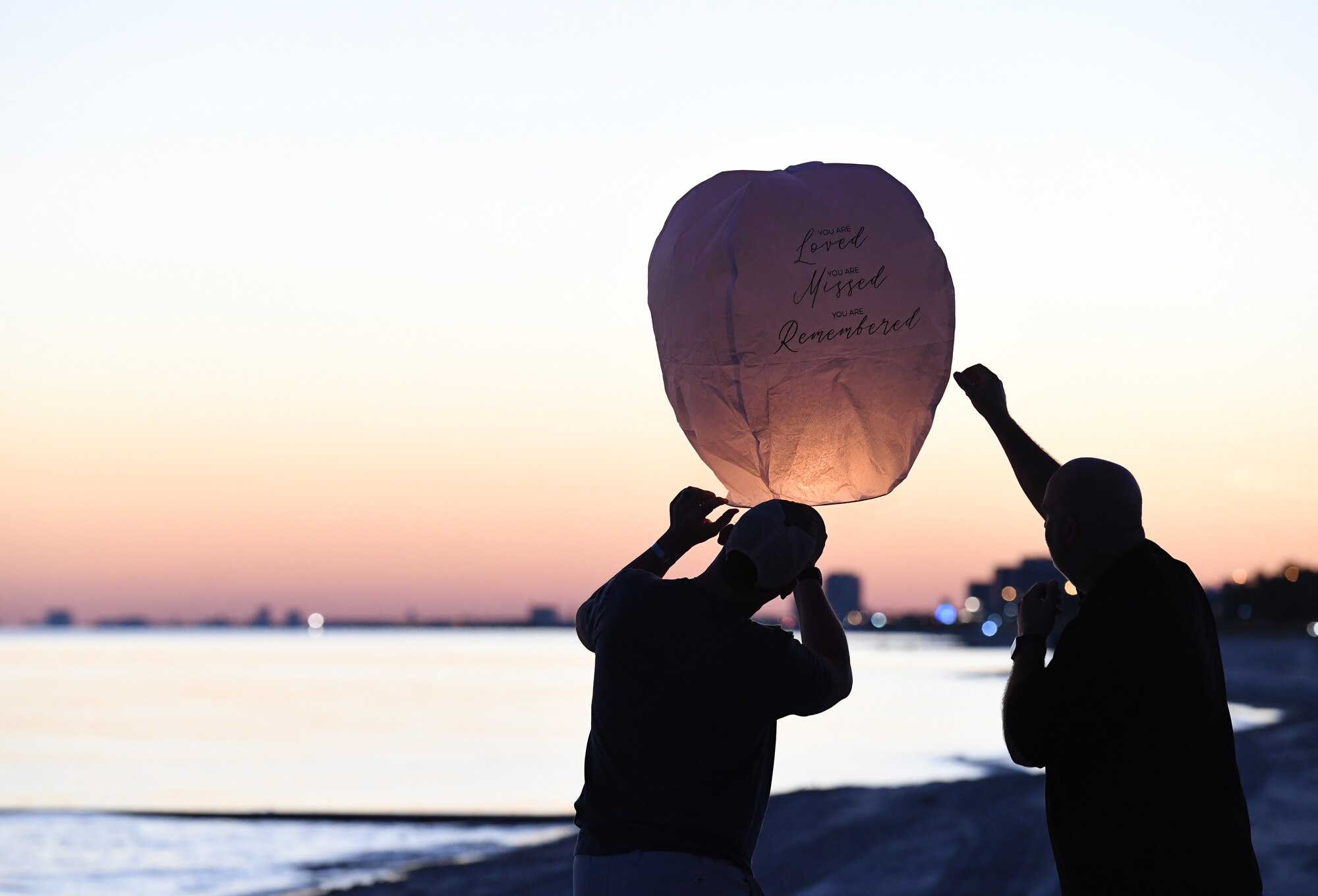 Military family members release a lantern during the Air Force Families Forever Fallen Hero Sky Lantern Lighting on the Biloxi Beach, Mississippi, Sept. 24, 2021. The event, hosted by Keesler Air Force Base, included eco-friendly sky lanterns released in honor of fallen heroes. (U.S. Air Force photo by Kemberly Groue)