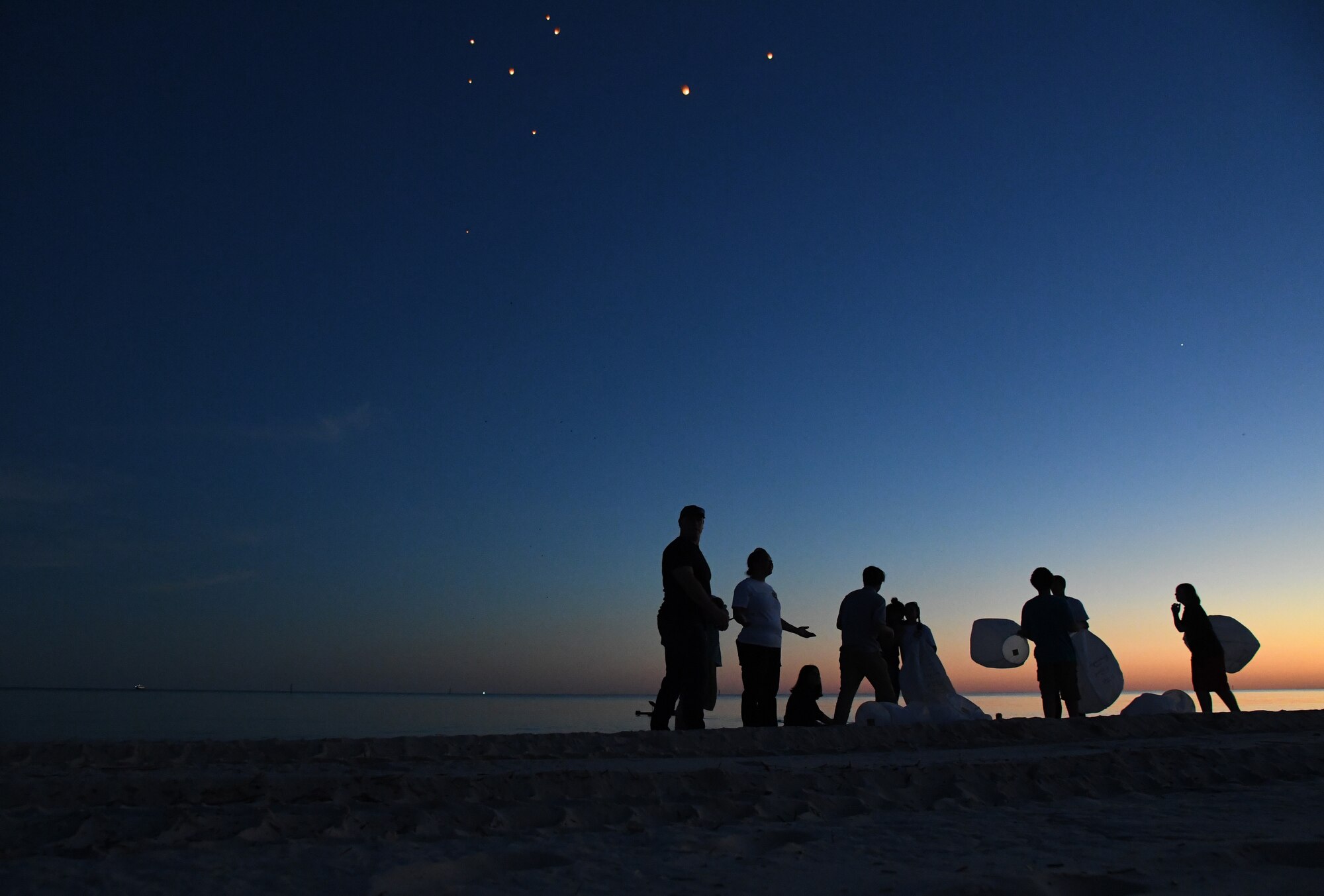 Military family members prepare to light and release lanterns during the Air Force Families Forever Fallen Hero Sky Lantern Lighting on the Biloxi Beach, Mississippi, Sept. 24, 2021. The event, hosted by Keesler Air Force Base, included eco-friendly sky lanterns released in honor of fallen heroes. (U.S. Air Force photo by Kemberly Groue)