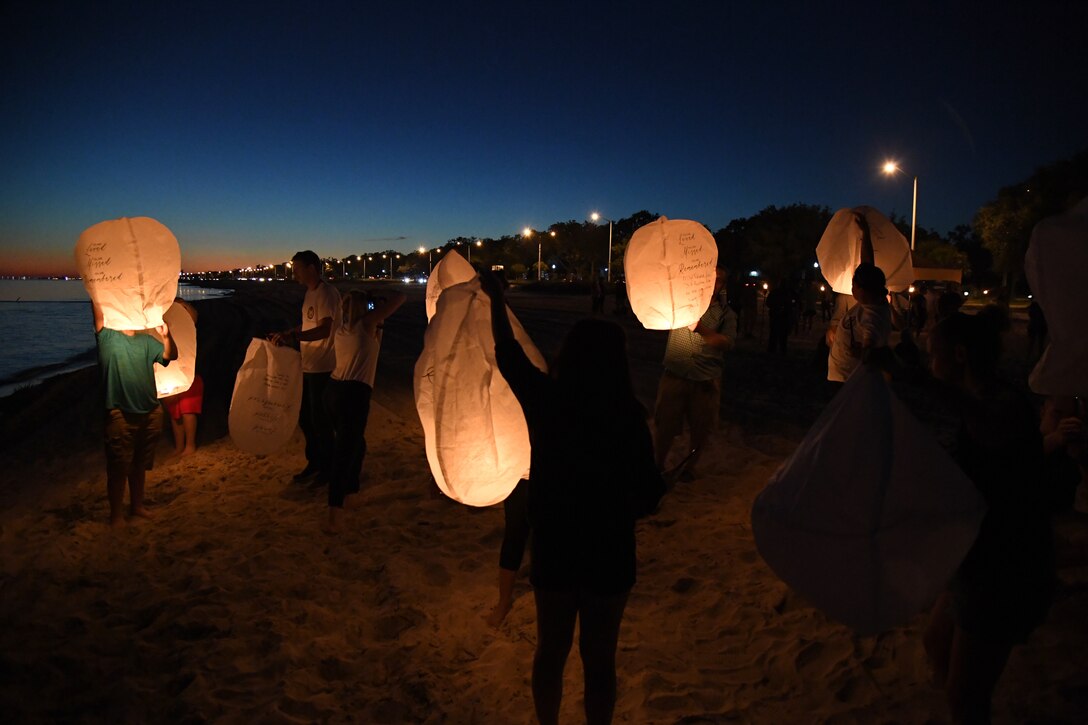 Military family members light lanterns during the Air Force Families Forever Fallen Hero Sky Lantern Lighting on the Biloxi Beach, Mississippi, Sept. 24, 2021. The event, hosted by Keesler Air Force Base, included eco-friendly sky lanterns released in honor of fallen heroes. (U.S. Air Force photo by Kemberly Groue)
