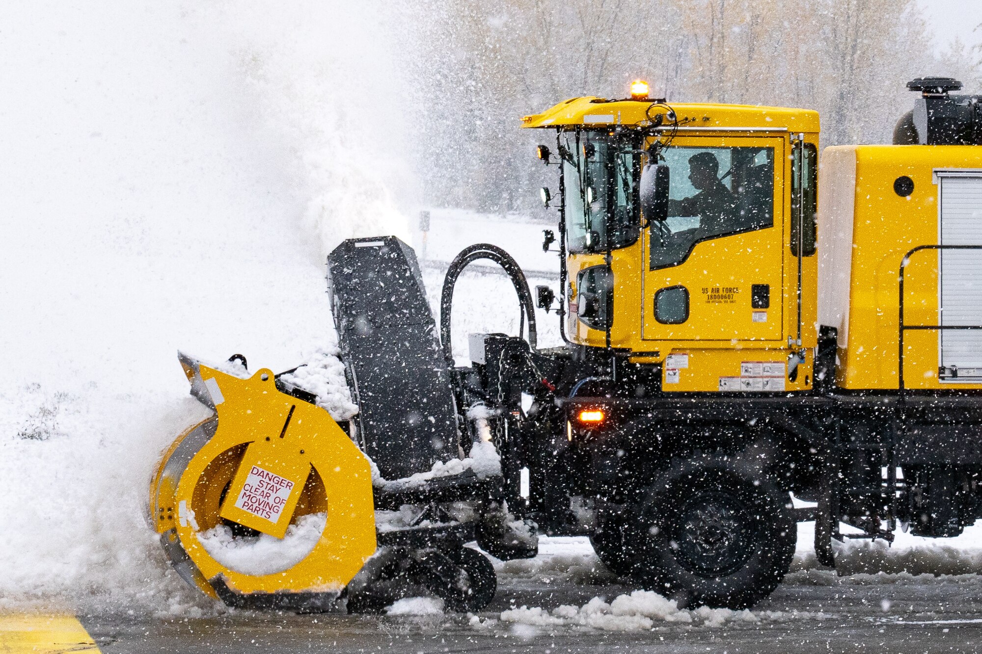 A U.S. Airman with the 773d Civil Engineer Squadron clears snow off the flight line after an early-season snowfall.