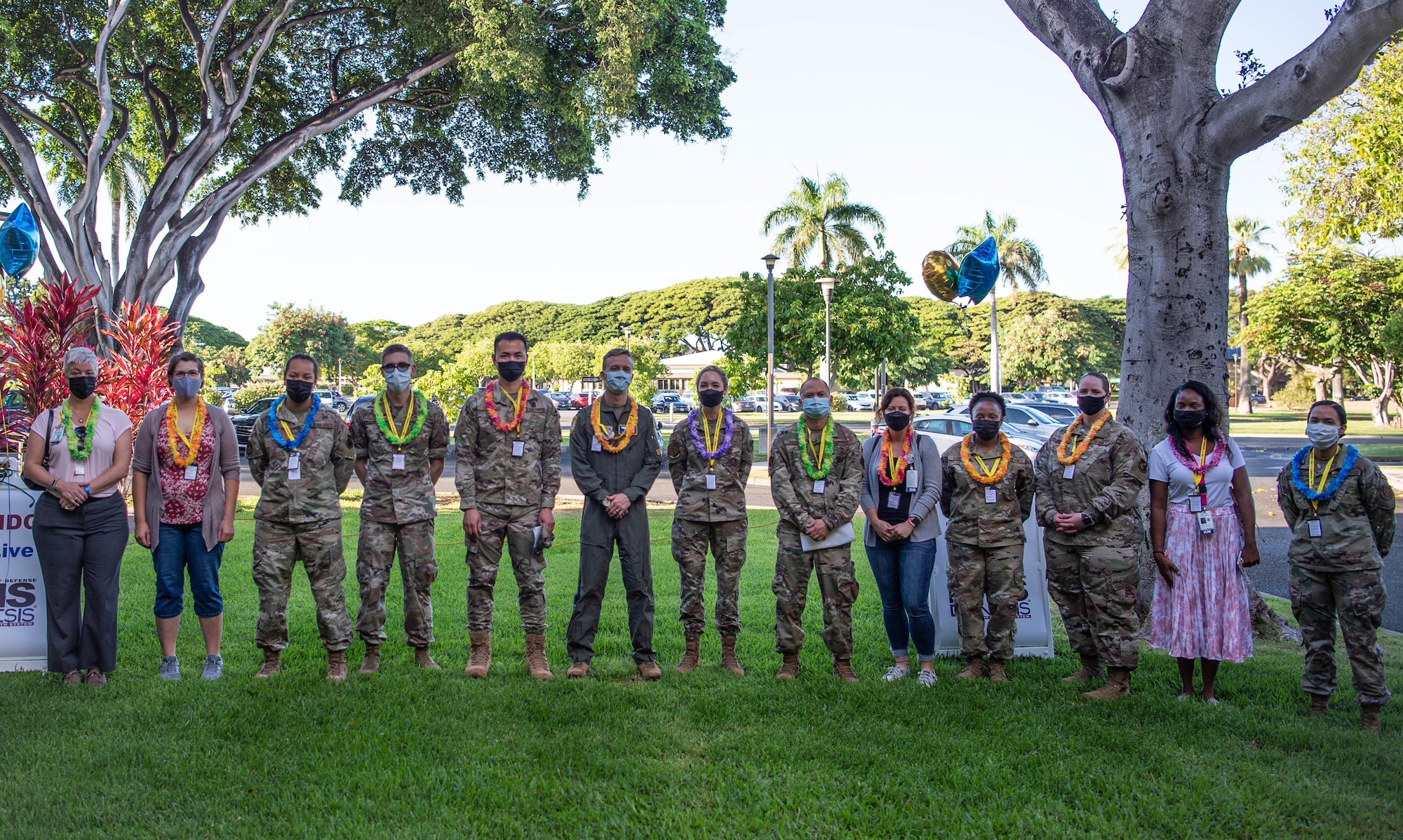 Active-duty and civilian Military Health System Genesis peer experts stand together after receiving leis during the MHS Genesis launch ceremony at Joint Base Pearl Harbor-Hickam, Hawaii, Sept. 25, 2021. The 12 peer experts volunteered to assist the 15th Medical Group during its initial utilization of MHS Genesis. The individuals were representatives from Elmendorf Air Force Base, Beale AFB, Fairchild AFB, Travis AFB, Nellis AFB, Fort Irwin, Naval Hospital Twentynine Palms, and Naval Medical Center San Diego. (U.S. Air Force by Senior Airman Alan Ricker)