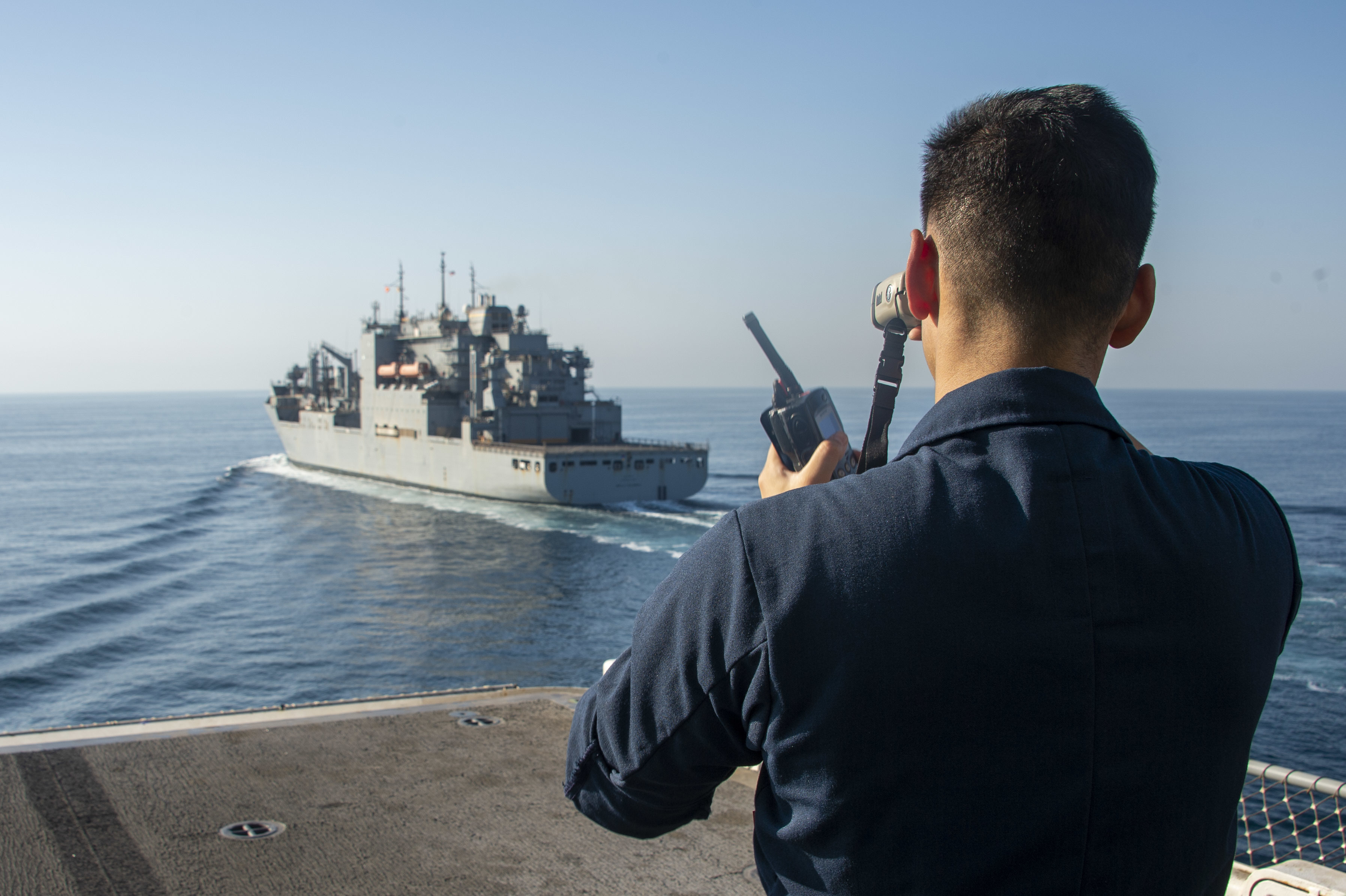Lt. j.g. Daniel Nailes uses a rangefinder aboard the amphibious assault ship USS Essex (LHD 2) during a replenishment-at-sea with the dry cargo and ammunition ship USNS Wally Schirra (T-AKE 8).