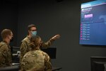 Maj. Richard Frantz, 272nd Cyber Operations chief of training, explains the Threat Cloud program to Senior Airmen Kelsie Hubbart and Micah Sage, cyber operators on the operations floor at Battle Creek Air National Guard Base, Michigan, Sept. 14, 2020. Threat Cloud was used to improve traffic conditions for the state of Michigan during Operation Resilience, Innovative Readiness Training.