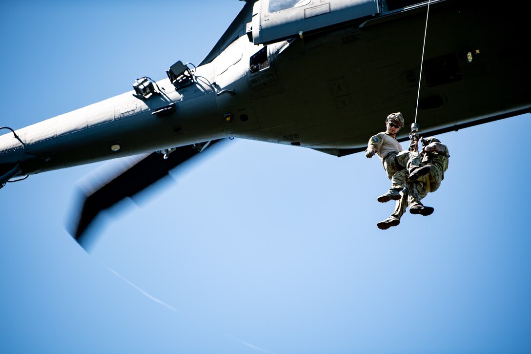 Photo of Airmen rappelling from a helicopter