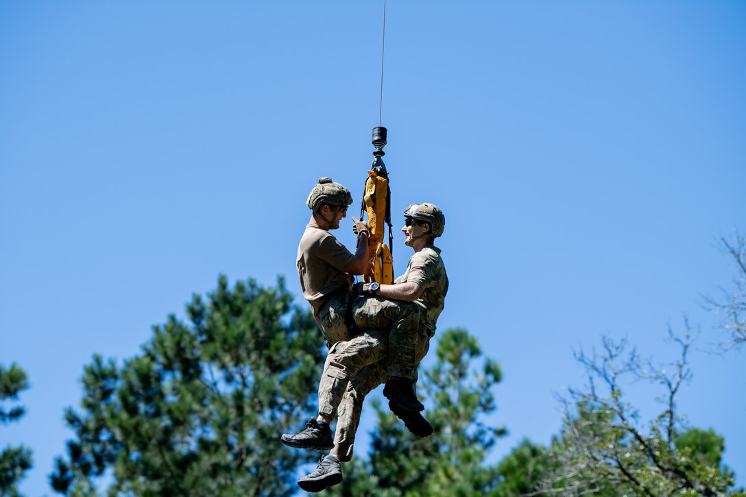 Photo of Airmen rappelling from a helicopter