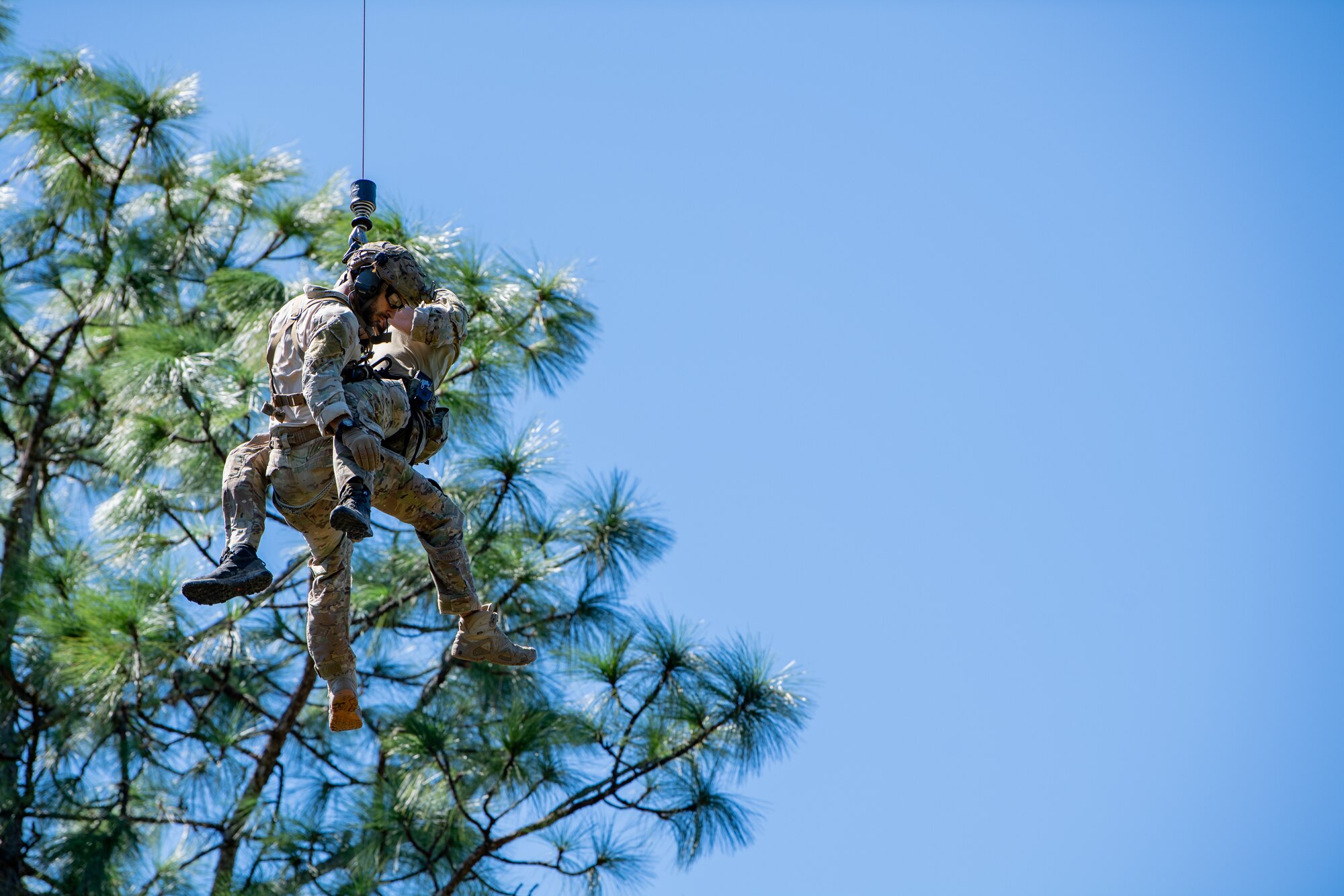 Photo of Airmen rappelling from a helicopter