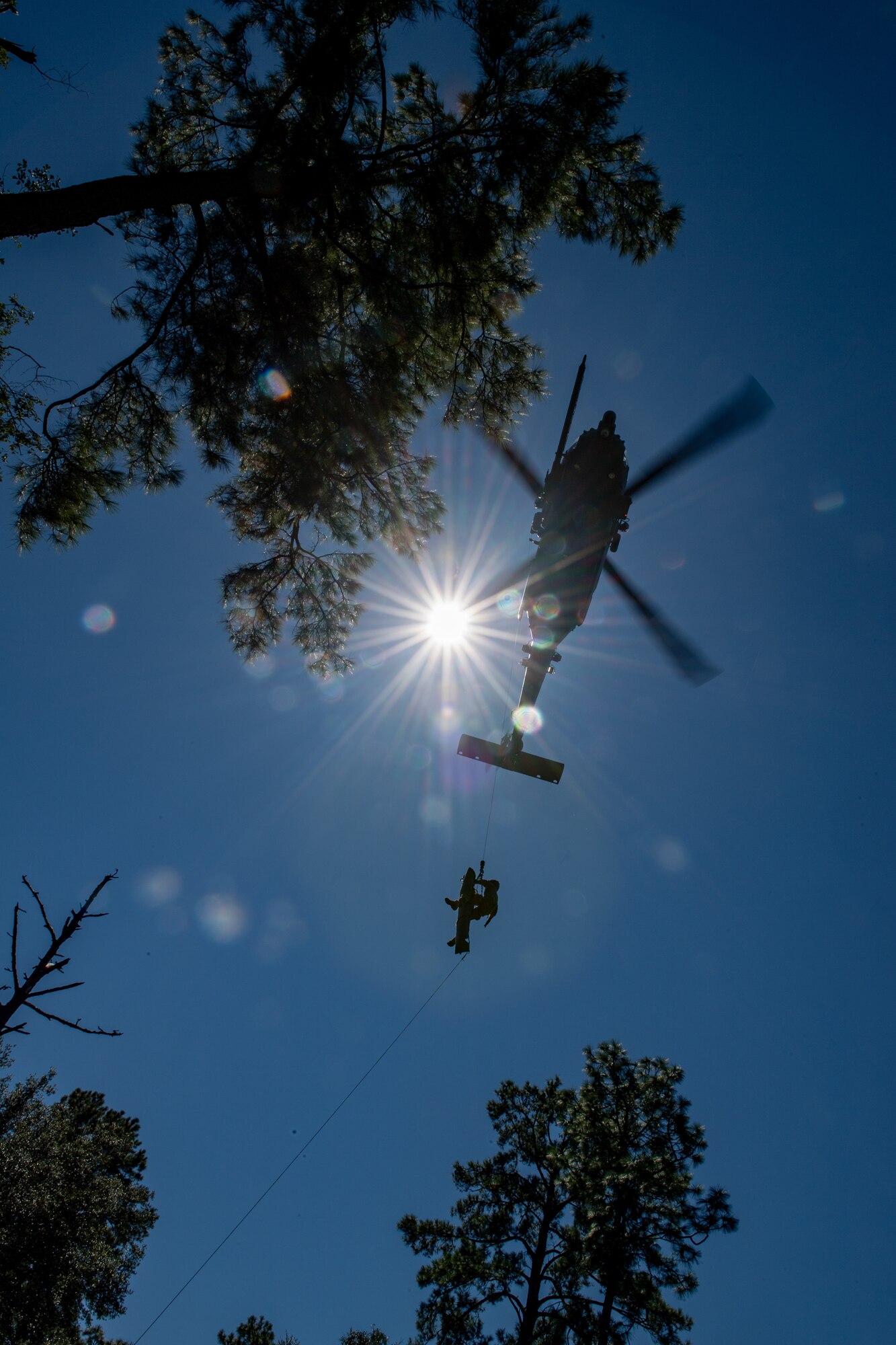 Photo of Airmen rappelling from a helicopter