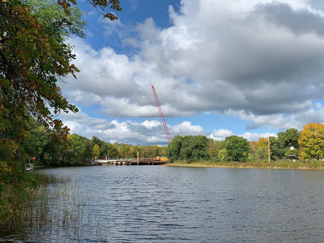 A lake surrounded with trees and a crane in the background.
