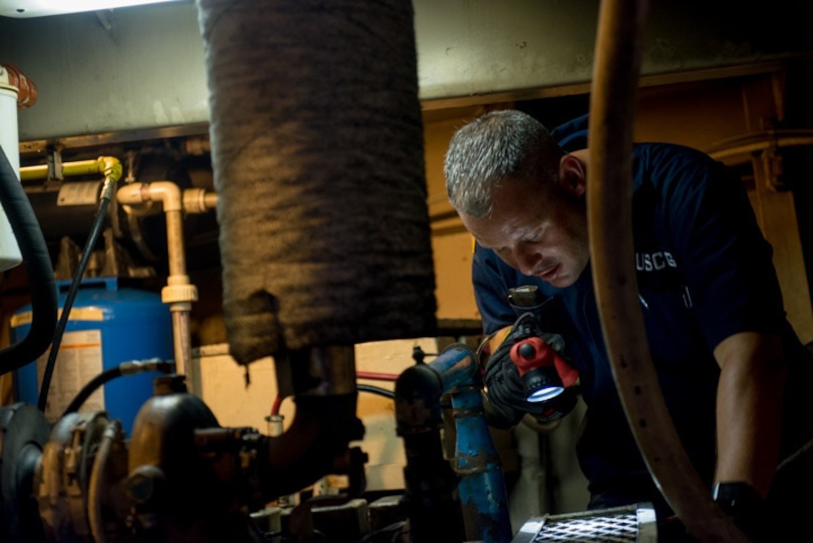 Chief Warrant Officer Aaron Studie examines a ship’s engine room as part of his domestic vessel inspection, July 14, 2015. The evolution of marine inspection has lead to regulations that protect the environment, provide a standard for the seaworthiness of the vessel and reliability of emergency equipment. (U.S. Coast Guard photo by Petty Officer 2nd Class David R. Marin)