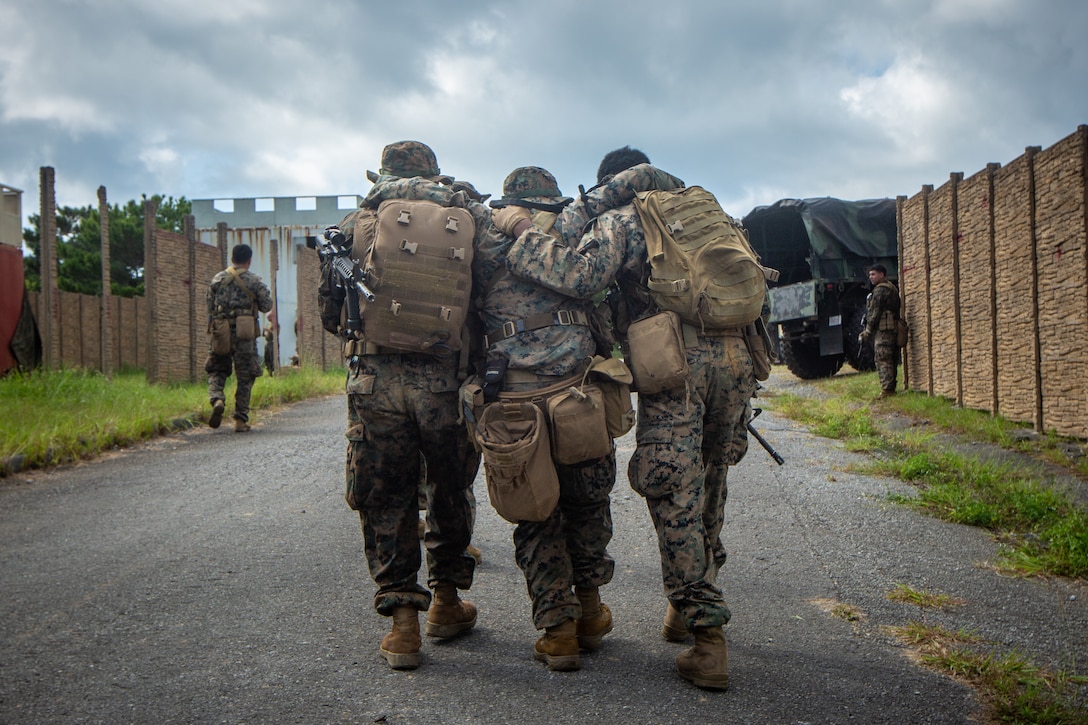 U.S. Marines assigned to 5th Air Naval Gunfire Liason Company, III Marine Expeditionary Force Information Group, simulate a buddy carry during a patrol while conducting a communications planning exercise on Camp Hansen, Okinawa, Japan, Sept. 23, 2021. The Marines practice patrolling to allowthem to  move from position to position tactically and safely under combat conditions. III MIG functions as the vangaurd of III MEF, operating in the Indo-Pacific region's information environment, and supports Marine Air Ground Task Force operations with communications, intelligence, and supporting arms liason capabilities.