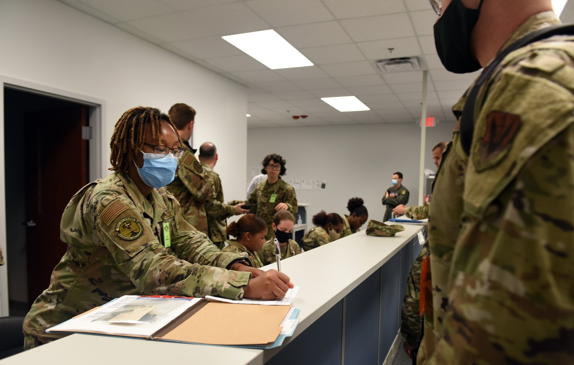 Photo shows Airmen talking with personnel behind counter.