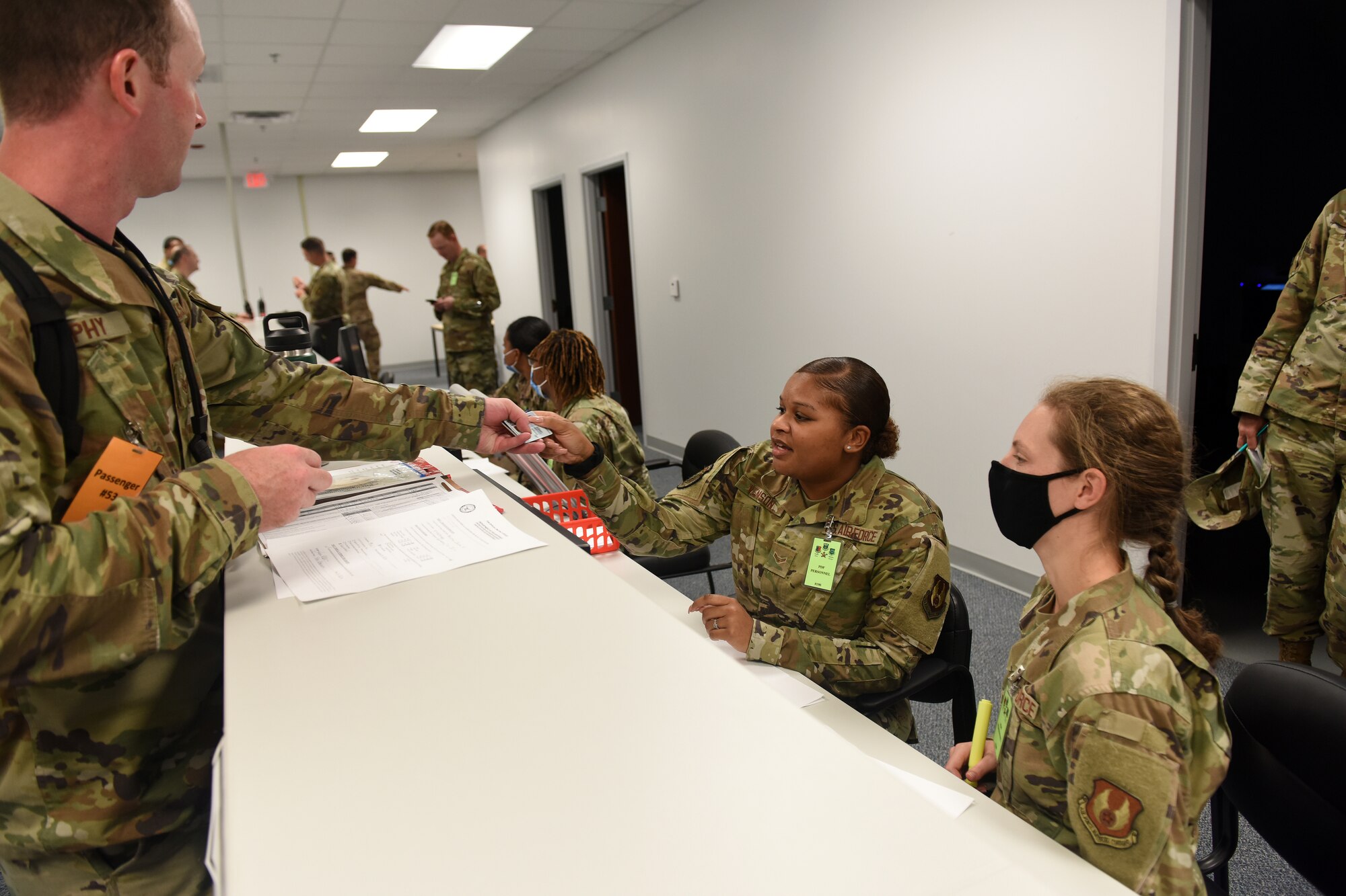 Photo shows Airmen talking with personnel behind counter.