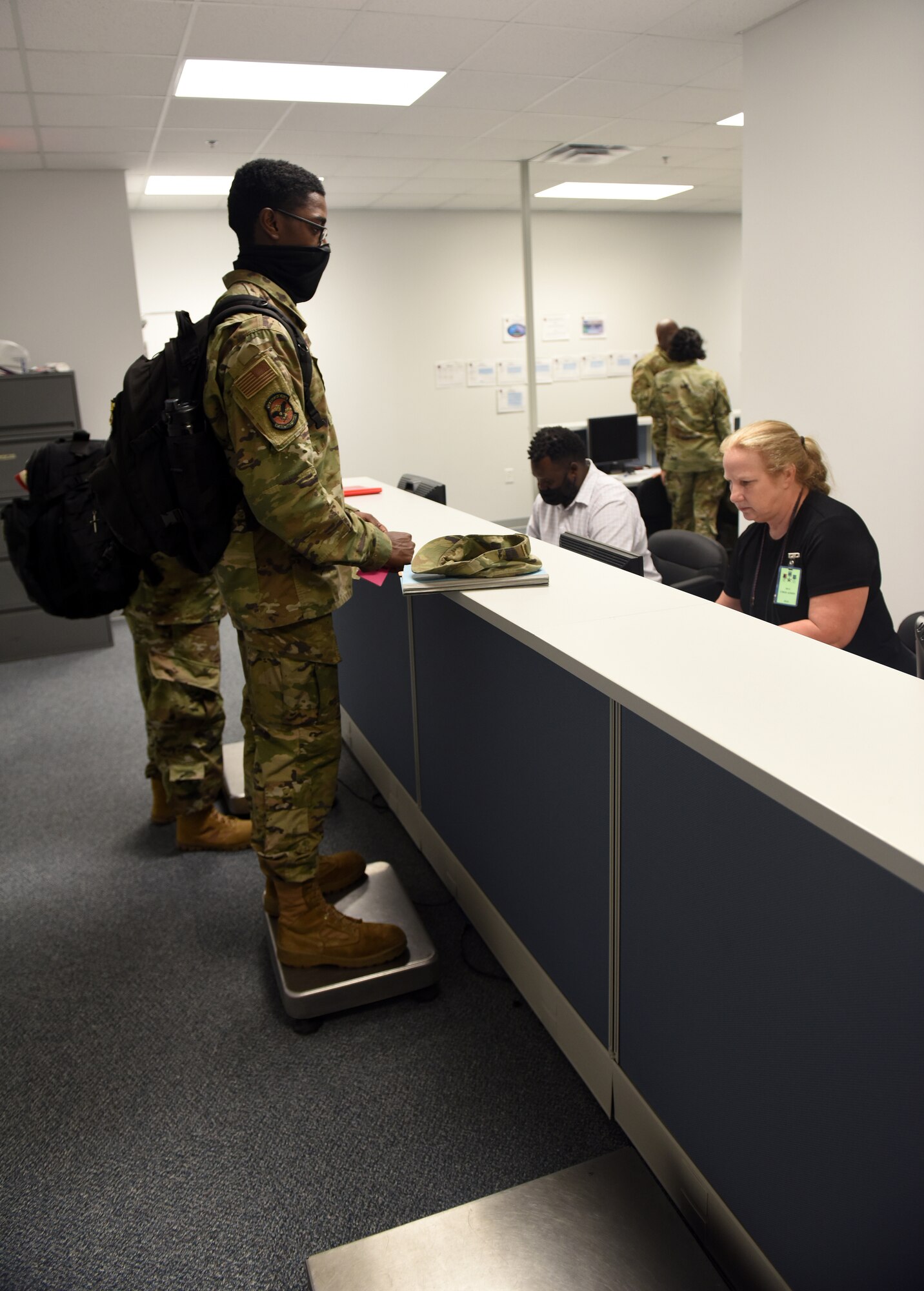 Photo shows Airmen walking by counter with personnel behind camera.