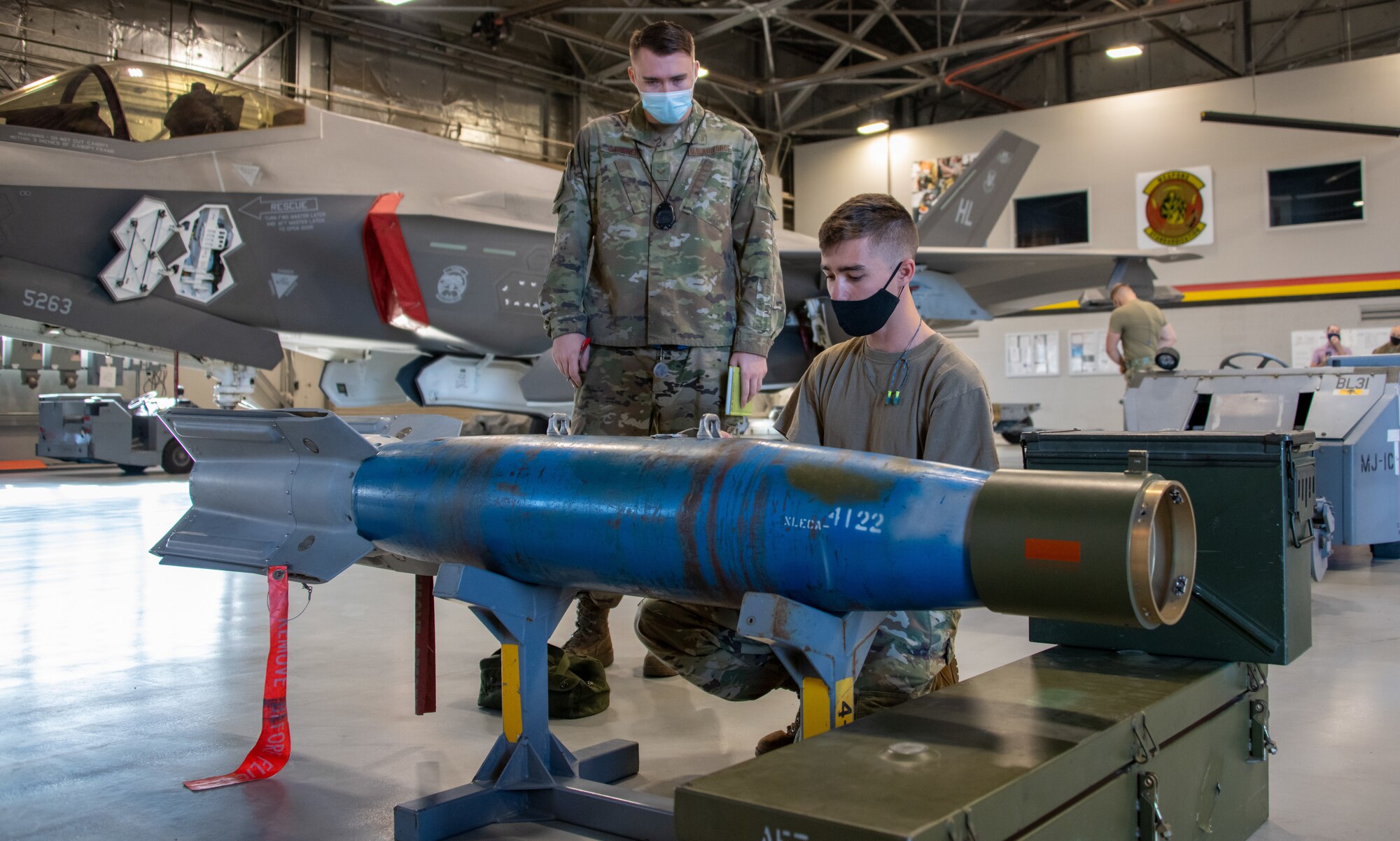 A judge looks over the shoulder of U.S. Air Force Staff Sgt. Connor Hansen from the 419th Aircraft Maintenance Squadron during a weapons load competition at Hill Air Force Base, Utah on Sept. 24, 2021. The quarterly competition focuses on speed, accuracy, and safety, ensuring standard loading procedures and proficiency across the wings. (U.S. Air Force photo by Senior Airman Erica Webster)