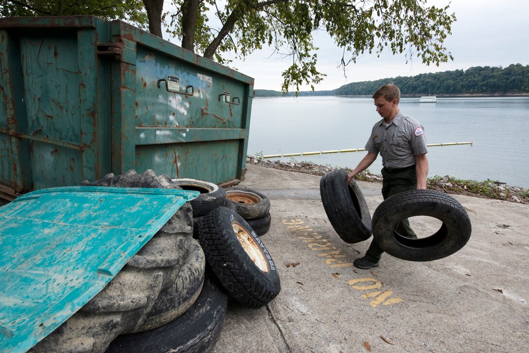 Park Ranger Dylan Norton carries tires collected from the shoreline of Lake Cumberland to a collection point at Waitsboro Recreation Area in Somerset, Kentucky, Sept. 25, 2021. As a member of the U.S. Army Corps of Engineers Nashville District staff at the lake, he helped organize the annual cleanup event and worked with partners and volunteers to pick up tons of trash. (USACE Photo by Lee Roberts