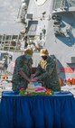 Rear Adm. Brendan McLane, commander, Naval Surface Force Atlantic, left, and Rear Adm. Brian Davies, commander, Submarine Group Two, right, cut a cake following introducing the Task Group Greyhound Initiative (TGG) aboard the guided-missile destroyer USS Thomas Hudner (DDG 116). TGG is a force generation initiative, inside the Optimized Fleet Response Plan (OFRP) construct, designed to provide the Fleet with predictable, continuously ready, and fully certified warships ready to accomplish the full range of fleet tasking. (U.S. Navy photo by Mass Communication Specialist 3rd Class Aaron Lau/Released)