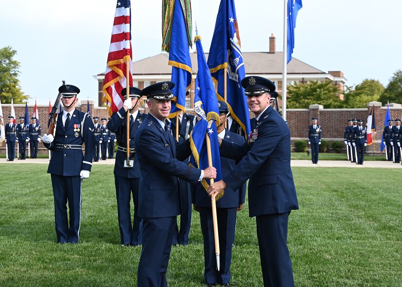 U.S. Air Force Maj. Gen. Joel D. Jackson, Air Force District of Washington and the 320th Air Expeditionary Wing commander, left, receives the 11th Wing guidon from Col. Mike Zuhlsdorf during a change of command ceremony at Joint Base Anacostia-Bolling, Washington, D.C., Sept. 28, 2021. Zuhlsdorf commanded JBAB and the 11th Wing during the Department of Defense’s first-ever joint base lead service transfer in 2020, during which the Air Force took control of the installation from the Navy. Zuhlsdorf relinquished command to incoming commander Col. Cat Logan. (U.S. Air Force photo by Staff Sgt. Kayla White)