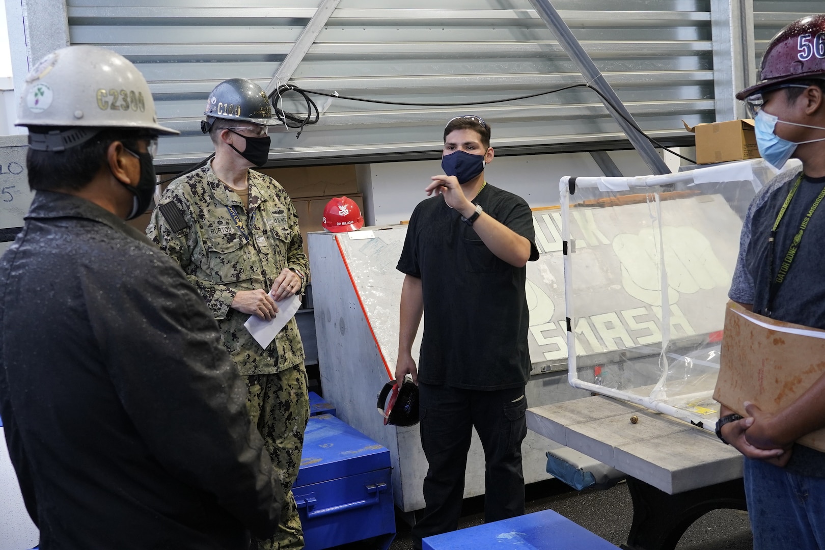 Pipefitter Apprentices Francis Dumlao and Alex Soulliere explain to former Pearl Harbor Naval Shipyard and Intermediate Maintenance Facility Commander, Capt. Greg Burton, and former Nuclear Engineering and Planning Manager, Kaipo Krowell how the nitrogen is hooked up from a riser with a line that runs inside USS Mississippi (SSN-782), blowing nitrogen air inside and having it bleed outside into the open air.