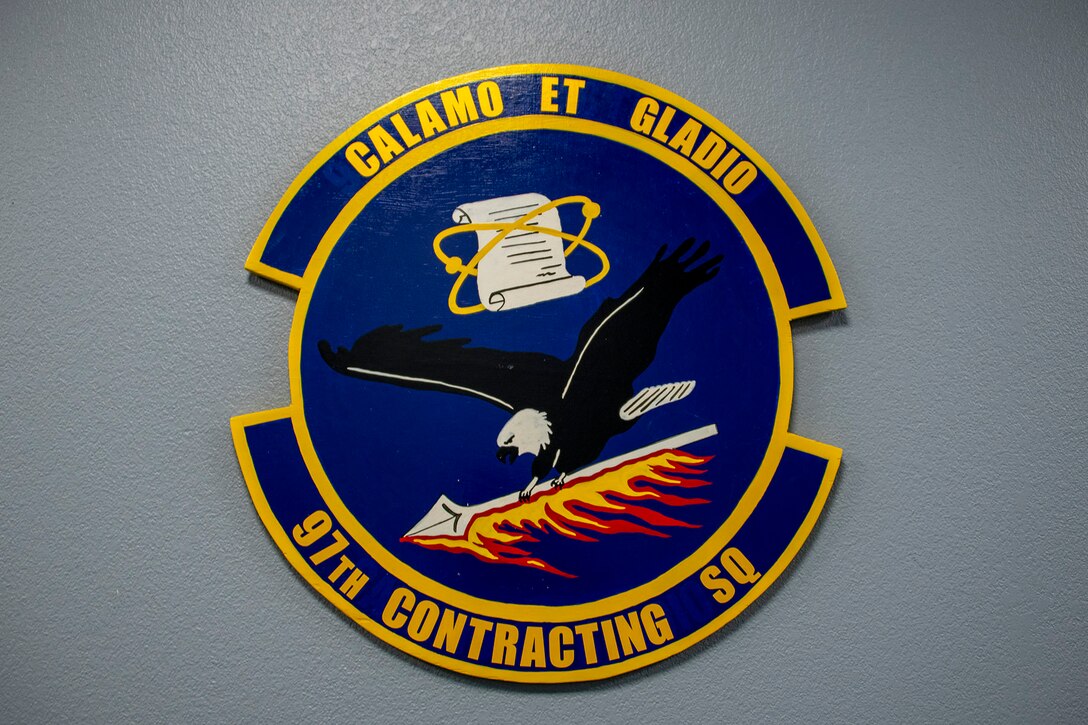 The new emblem for the 97th Contracting Squadron (CONS) is hung on the wall at Altus Air Force Base, Oklahoma, Aug. 3, 2021. Col. Blaine Baker, 97th Air Mobility Wing commander, redesignated the 97th Contracting Flight to the 97th CONS due to the manning assigned to the squadron. (U.S. Air Force photo by Senior Airman Amanda Lovelace)
