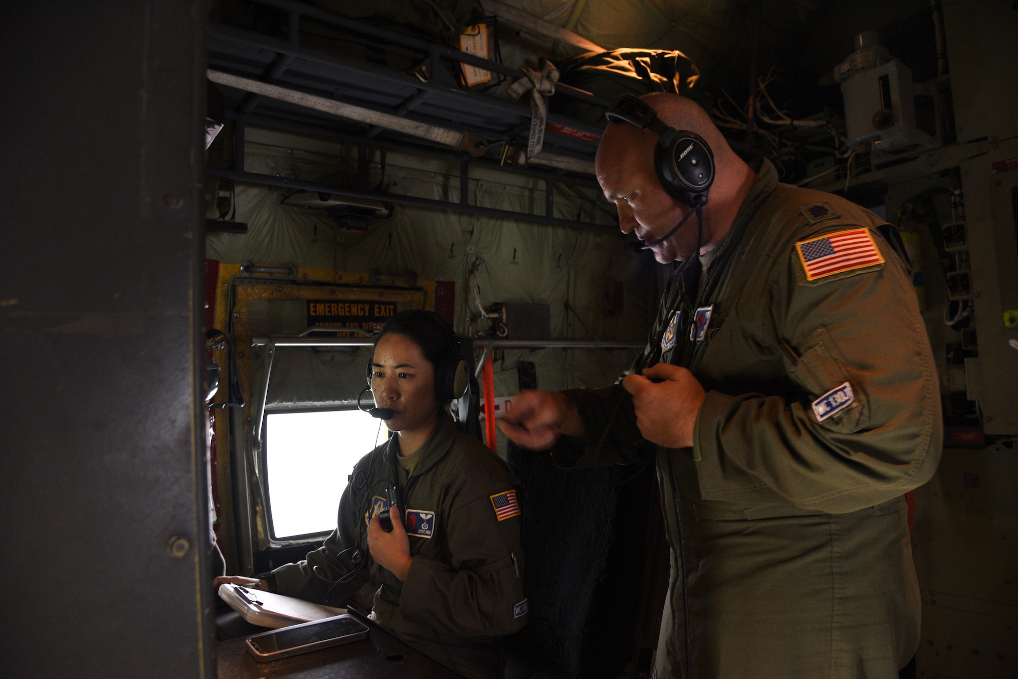 Lt. Col. Ryan Rickert and Maj. Joyce Hirai, 53rd Weather Reconnaissance Squadron aerial reconnaissance weather officers, discuss the weather data as the Hurricane Hunters fly into Hurricane Sam, Sept. 27, 2021. Hurricane Sam had downgraded to a category 3 hurricane when the AF Reserve Hurricane Hunters entered, but was intensifying before they headed back. The Hurricane Hunters gather data weather data from dropsondes and aircraft sensors, which is given to the National Hurricane Center to assist them with their forecasts and storm warnings. (U.S. Air Force photo by Jessica L. Kendziorek)
